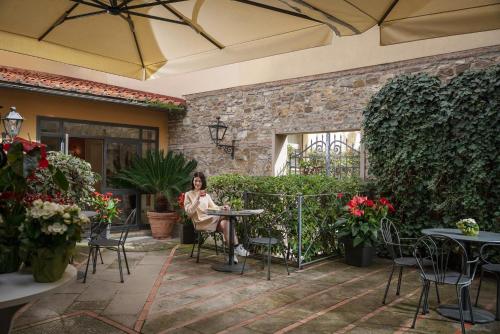 a woman sitting at a table in a patio at Grand Hotel Adriatico in Florence
