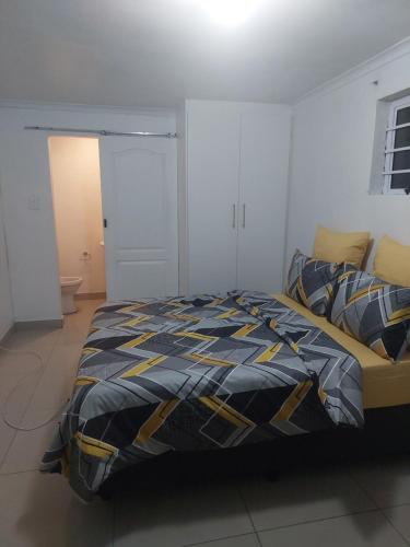a bedroom with a bed with a blue and yellow comforter at Little Angel Studio in Parow