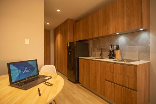 a laptop computer sitting on a wooden table in a kitchen at Edificio QO 97 By Jalo in Bogotá