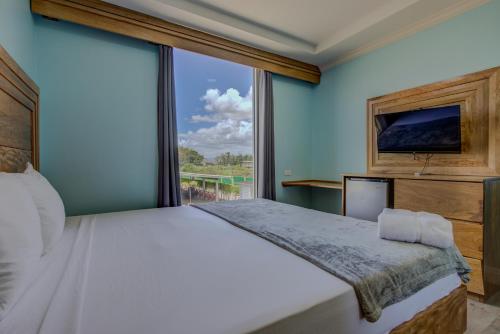 a bedroom with a large bed and a large window at Airport Suites Hotel in Piarco