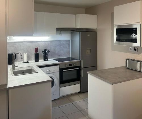 une cuisine avec un évier et une cuisinière four supérieur dans l'établissement L'Escale Sétoise - Méditerranéenne, à Sète