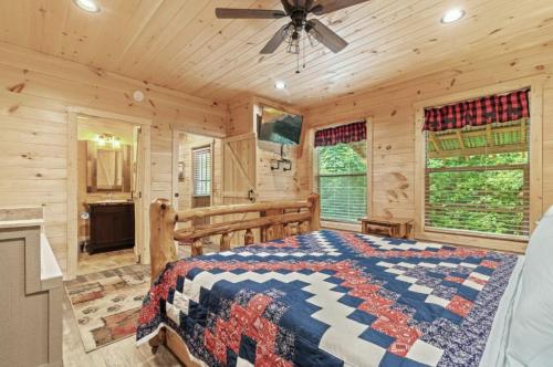 a log cabin bedroom with a bed and a ceiling fan at Falling Brook – Cozy Creekside Cabin with Hot Tub, Game Loft & Dog-Friendly Comfort in Gatlinburg