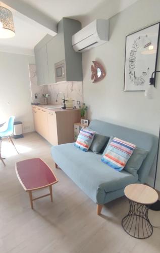 un salon avec un canapé bleu et une cuisine dans l'établissement Collioure au Faubourg T2 à 3min des plages, Clim, avec petit Parking, à Collioure