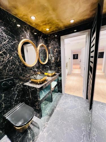 une salle de bain avec du marbre noir et des miroirs dorés dans l'établissement Maison Chez Nous - villa à 10min de Monaco, à Cap d'Ail