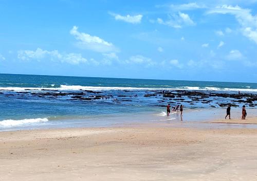 a group of people walking in the water on a beach at Casa Jasmine Taíba in Taíba