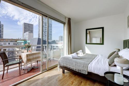 une chambre avec un lit et une grande fenêtre dans l'établissement Eiffel residence Gustave, à Paris