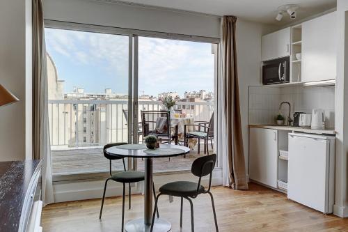 une cuisine avec une table et des chaises ainsi qu'une grande fenêtre dans l'établissement Eiffel residence Gustave, à Paris