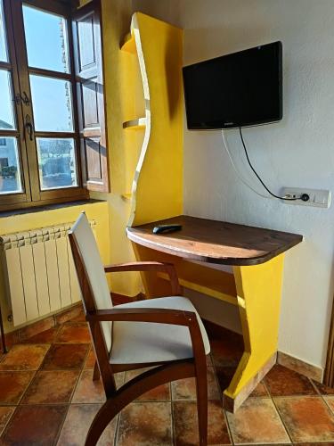 a desk with a chair and a television on a wall at Hotel y Apartamentos Penarronda Playa in Castropol