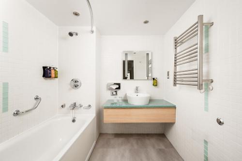 a bathroom with a sink and a tub and a mirror at Holiday Inn Birmingham City by IHG in Birmingham