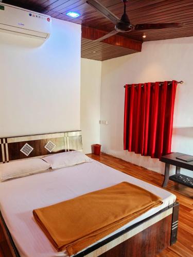 a bedroom with a bed with a red curtain at River Garden Guest House in Jambhulpāda