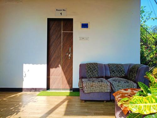 a living room with a couch in front of a door at Hotel River Garden Jambhulpada in Jambhulpāda