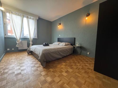 Un dormitorio con una cama y suelo de madera. en Rétro Lomme, en Lille
