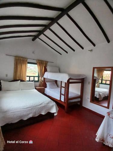 a bedroom with two beds and a mirror at HOTEL El CORZO DE LA VILLA in Villa de Leyva