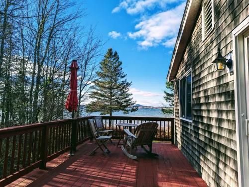 a patio with two chairs and an umbrella on a balcony at Tideside Beach House in Trenton