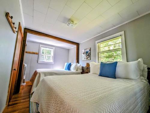 a bedroom with two beds with blue and white pillows at Lone Pine Oceanfront Cottage in Prospect Harbor