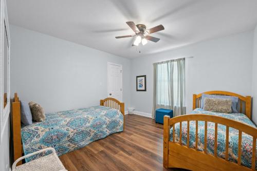 a bedroom with two beds and a ceiling fan at Peaceful Fairhope Retreat-Large home on 1 acre lot in Fairhope