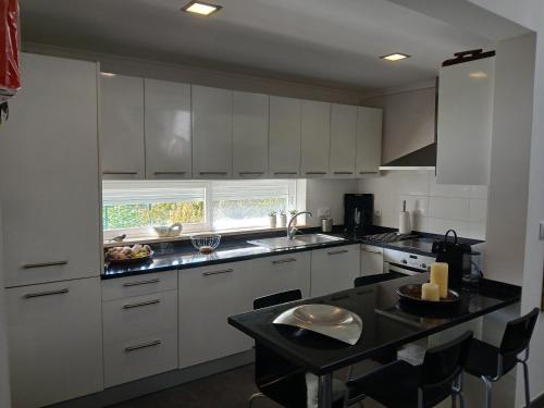 a kitchen with white cabinets and a black counter top at Moradia no Meco in Sesimbra