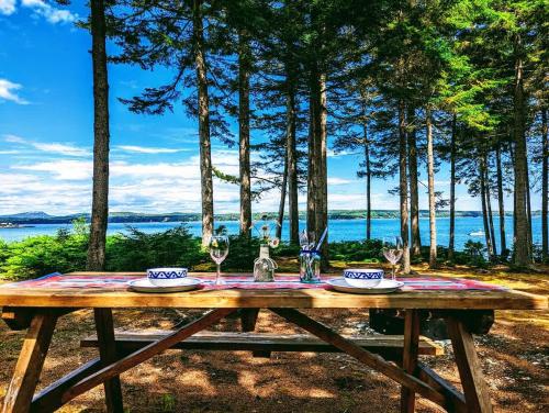 a wooden picnic table with wine glasses on it at Couples Cove Cottage in Ellsworth