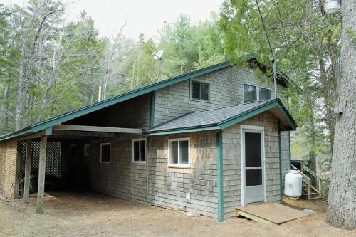 una piccola casa con un portico nel bosco di Somes Pond Island Cottage a Southwest Harbor
