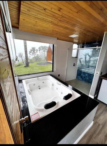 a large bath tub in a room with a window at Refúgio da Realeza in Urubici