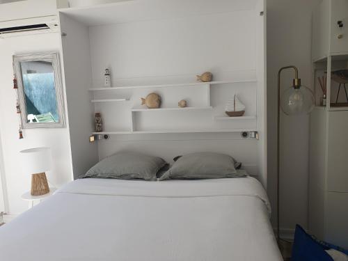a bedroom with a white bed and white shelves at Le B - A 200 m de la plage in Arcachon