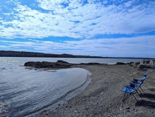 a blue chair sitting on a beach near the water at Lobster Pound Beach House in Hancock