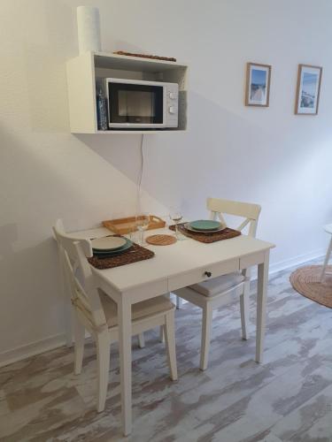une table blanche avec deux chaises et un four micro-ondes dans l'établissement Le B - A 200 m de la plage, à Arcachon