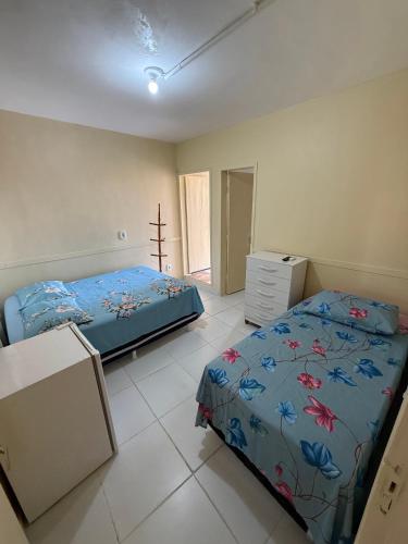 a bedroom with two beds and a dresser in it at Pousada Extensão Sabrinna in Maceió