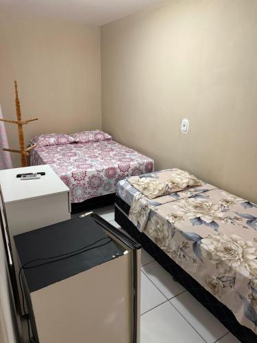 a room with two beds and a refrigerator in it at Pousada Extensão Sabrinna in Maceió