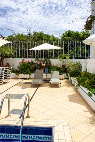 a patio with two chairs and an umbrella and a pool at Blue Calm in Daratso