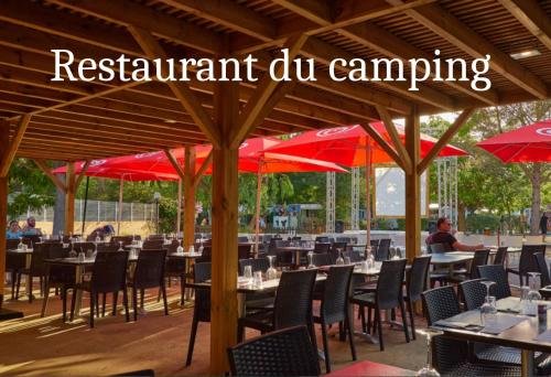a restaurant with tables and chairs with red umbrellas at mobilhome au domaine des iscles emplacement 137 in La Roque-dʼAnthéron