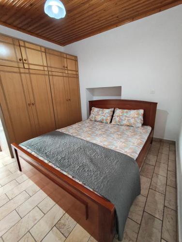 a bedroom with a bed with a wooden headboard and cabinets at Traditional Stone House in Mantamádos