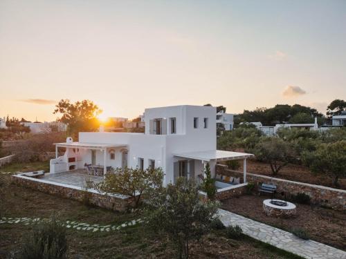 a white house with the sunset in the background at Cycladic Wine Press House in Aliki