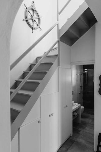 a room with a staircase with a clock on the wall at Cycladic Wine Press House in Aliki