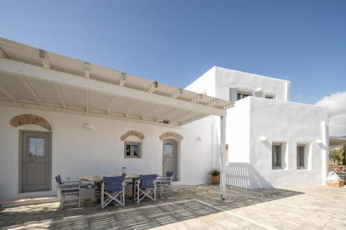 a white house with a table and chairs on a patio at Cycladic Wine Press House in Aliki
