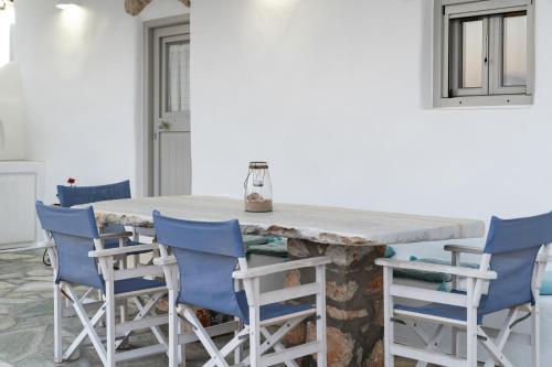 a kitchen with a large stone table with blue chairs at Cycladic Wine Press House in Aliki
