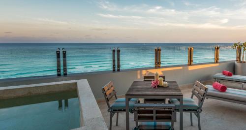 a table and chairs on a balcony with the ocean at Park Royal Beach Cancun - All Inclusive in Cancún