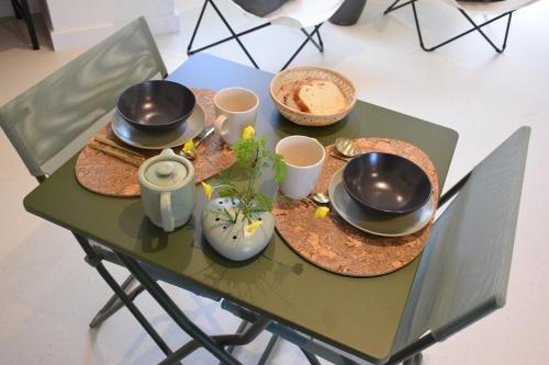 Les Herbes Folles في Courcoury: طاولة خضراء عليها صحون واكواب