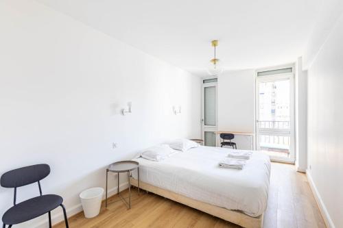 - une chambre blanche avec un lit et deux chaises dans l'établissement GuestReady - Stylish Stay in the Heart of Javel, à Paris