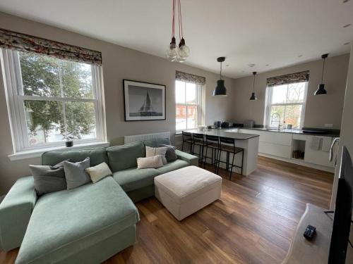 a living room with a green couch and a kitchen at Nomi Homes - New - The Coffers - Budleigh Salterton - Exmouth - Beach - Sleeps 4 in Exeter