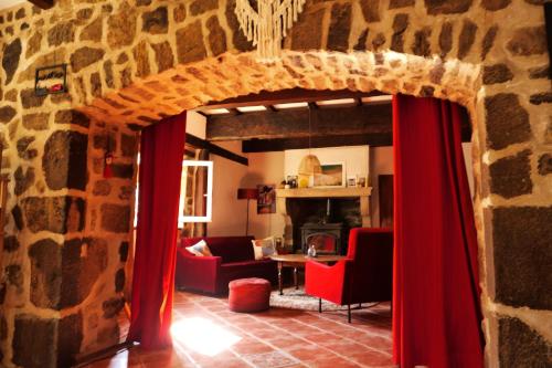 a living room with a stone wall and red curtains at Gîte La Loba in Pailharès
