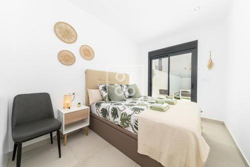 a bedroom with a bed and a chair and a window at Villa Perla de Pilar - Private pool and rooftop near Beach - by Oyoostays in Pilar de la Horadada