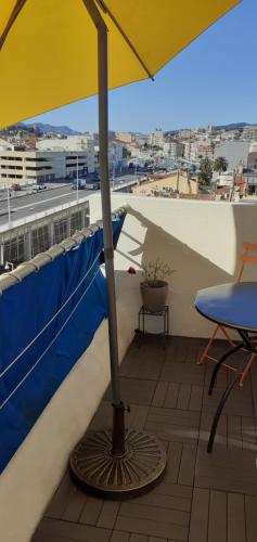 un parasol jaune sur un balcon avec une table dans l'établissement Le lutetia 06, à Cannes