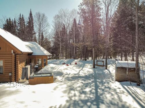 a log cabin in the snow next to a forest at Relaxing Sauna and Hot Tub, Near Ski Slopes,Trails in Mille-Isles