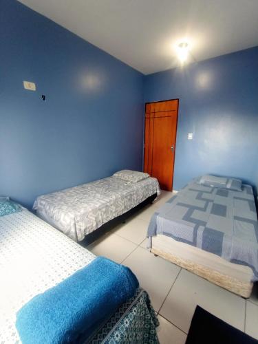 two beds in a bedroom with blue walls at Refúgio no Centro in Imperatriz