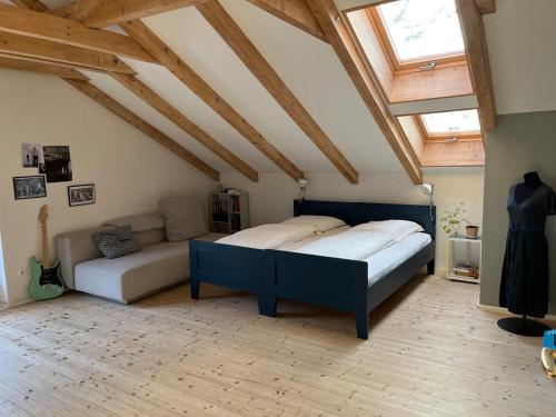 a bedroom with a bed and a couch in a attic at Künstlerhaus im Blauen Land für die grosse Familie in Ohlstadt