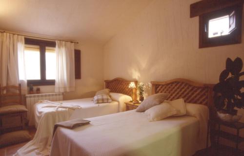 a bedroom with two beds and a window at Casa Rural Nelia in Villalba de la Sierra