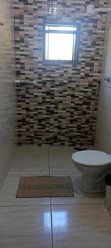 a bathroom with a toilet and a window at Rancho Recanto Verde in Capitólio
