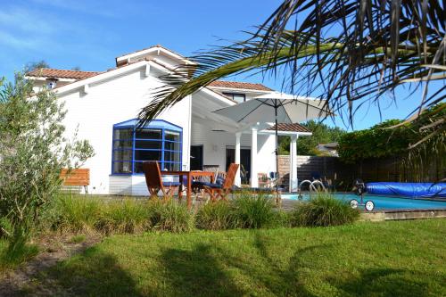 une maison blanche avec une piscine, une table et des chaises dans l'établissement Villa Destordeur, à Moliets-et-Maa