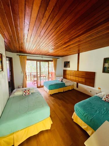 two beds in a room with a wooden ceiling at Mama Tungu hostel in Baños